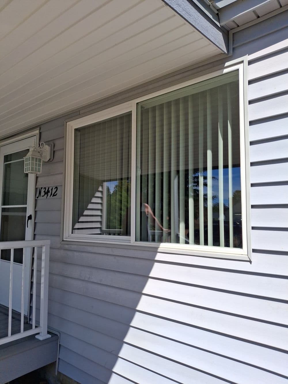 Modern window design with vertical blinds on a house exterior, bright outdoor lighting.