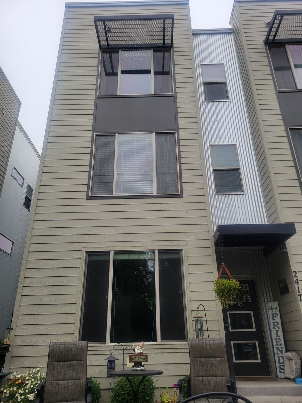 Modern multi-story building facade with large windows and outdoor seating area.