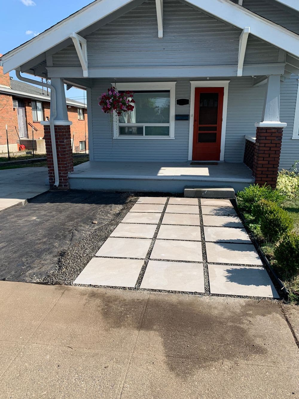 Front porch with new stone pathway, hanging flower basket, and freshly landscaped yard.