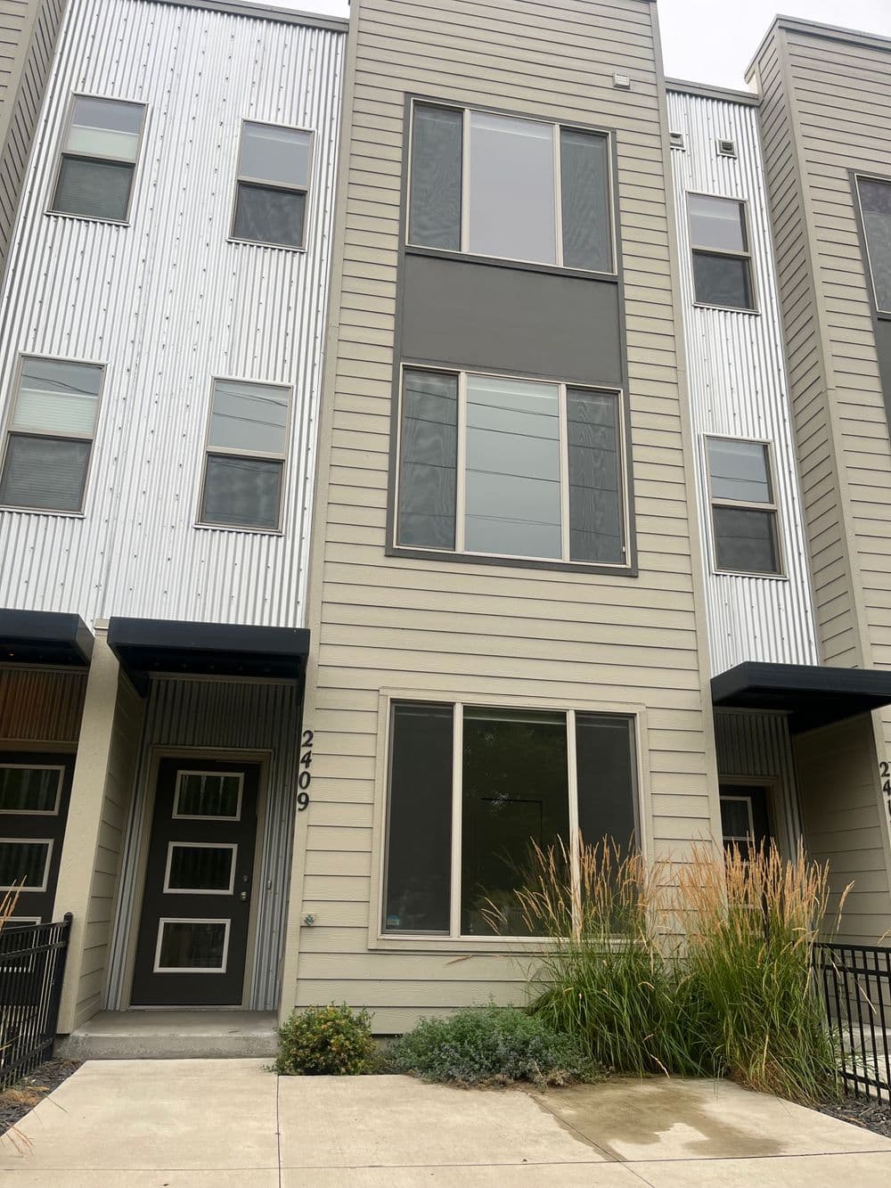 Modern townhouse exterior with large windows and landscaped entryway at 2409 address.