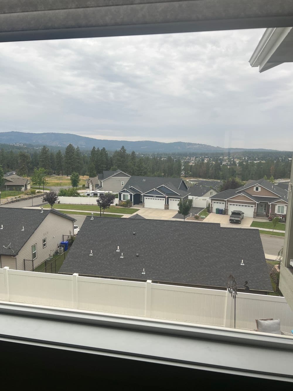 View from a window showcasing residential neighborhood and mountains in the background.