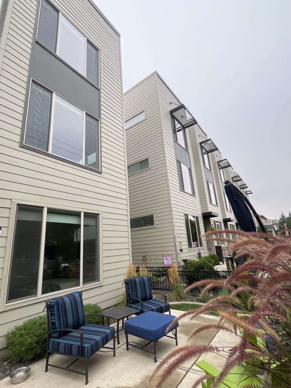 Modern townhouses with outdoor seating area and lush landscaping.