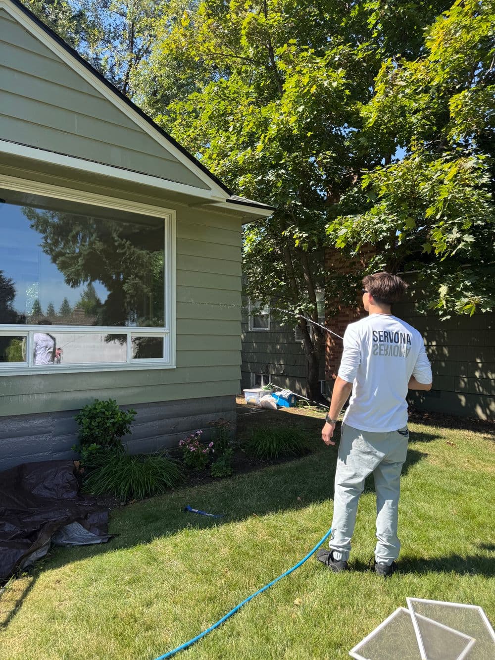 Residential exterior painting with a professional working on the home's green siding.